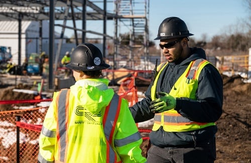 Two CRB construction workers on a job site discussing HammerTech and construction safety